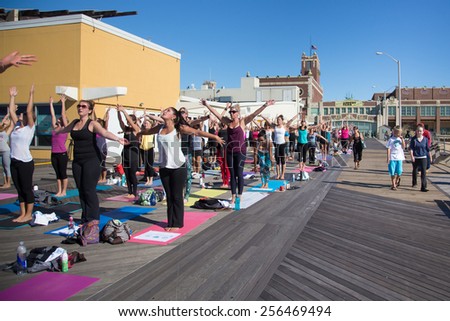 ASBURY PARK, NJ - SEPTEMBER 21, 2013:  People participating in outdoor yoga class on the boardwalk in Asbury Park, NJ on a Sunday morning.