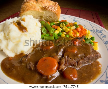 American comfort food; a heart dish of pot roast smothered in gravy, mashed potatoes and mixed vegetables.  This is a dish of real homecooked meat and potatoes.