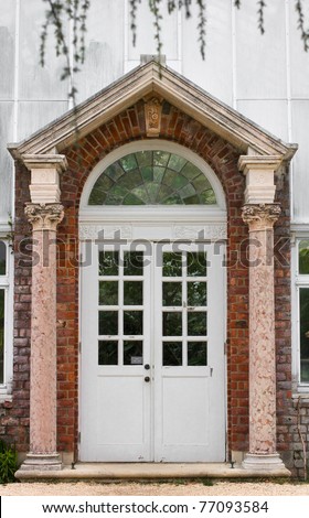 A lovely columned entrance with a french paned door leading to a greenhouse