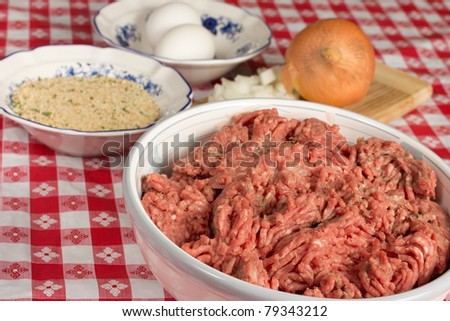 A bowl of chopped ground beef and assorted ingredients to prepare Italian meatballs