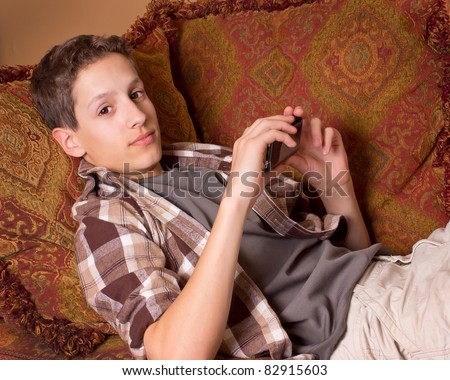 Handsome teenage boy relaxing while holding a cell phone mp3 player - stock photo