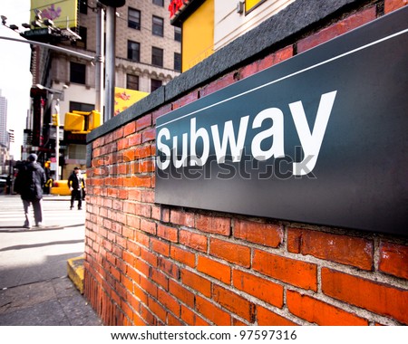 Subway entrance sign at a typical New York City intersection
