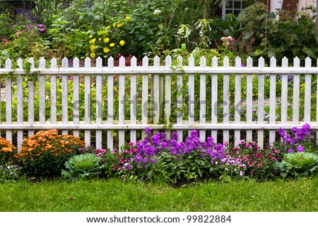 White picket fence with pretty flowers in a yard