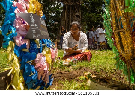 UBUD, BALI, INDONESIA - NOV 1: Hindu woman prays over graves during ceremony of the cremation of the Queen on November 1, 2013 in Ubud, Bali.