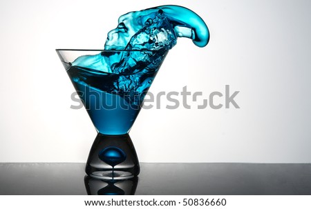 blue liquid pouring out of martini glass