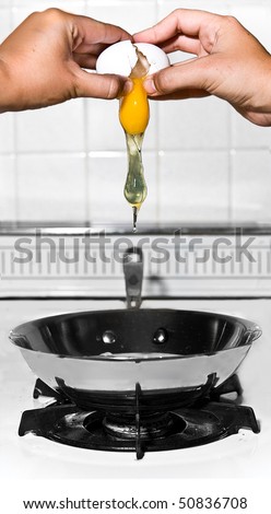 two hands crack egg over frying pan