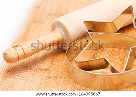 Wooden rolling pin and cookie cutters on kitchen board