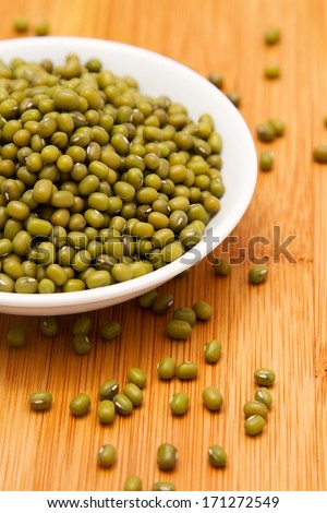 Mung beans in white bowl on wooden tabletop