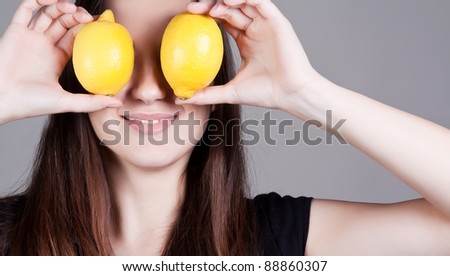 Portrait of young smiling woman with lemons in front of eyes