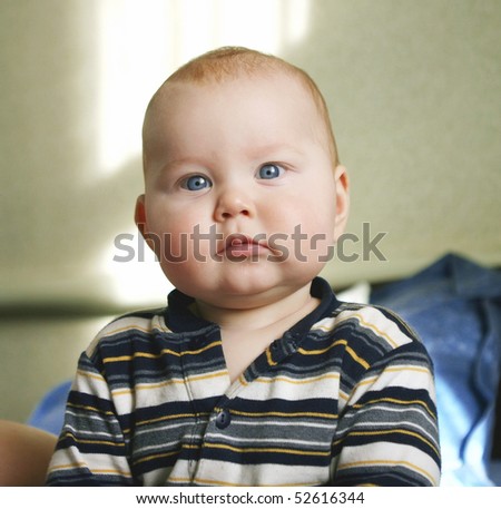 Portrait of beautiful little boy, looking with curiosity large blue eyes on the world
