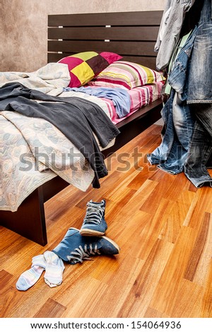 A bedroom with clothes and shoes in mess