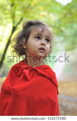 Little girl dressed as Little Red Riding Hood in the forest