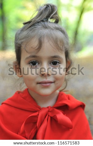 Little girl dressed as Little Red Riding Hood in the forest