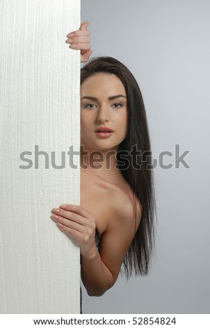 young woman looking out from behind the wall