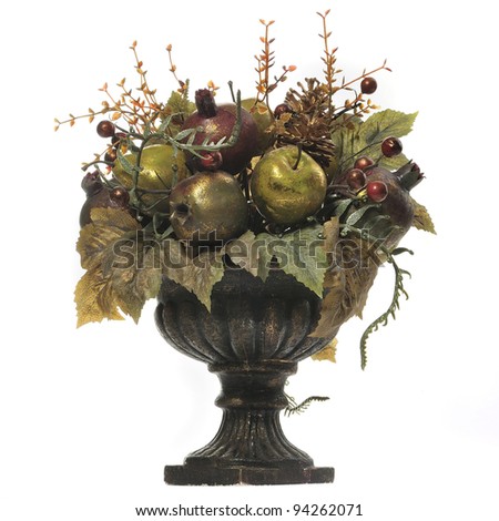 A bouquet of artificial fruits and flowers in an old vase
