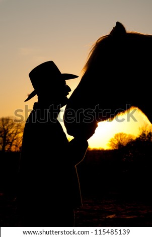 Horse and his cowboy silhouetted against a sunset, head to head