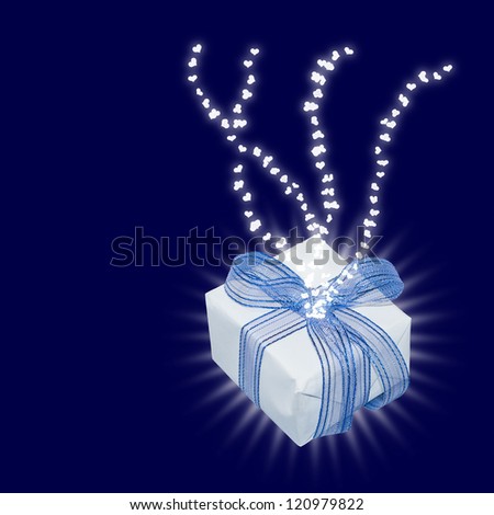 Magic gift with light rays and heart trails; on dark blue background with copy space