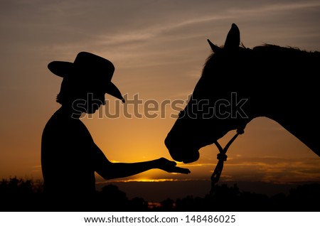 Silhouette of a girl in a cowboy hat with her horse - best friends together