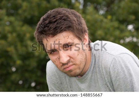 Dirty, sweaty, tired, young man taking a break, looking at the viewer