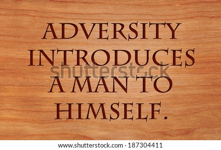 Adversity introduces a man to himself - quote by unknown author on wooden red oak background