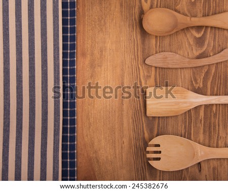 Blue and off white kitchen towels on dark wood background with a wooden utensils, with a slight vignette