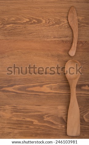 Wooden spoon and knife on the right side of dark wood tabletop, with copy space on the left
