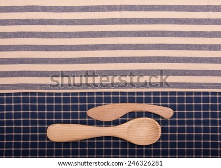 Wooden spoon and knife on blue and off white linen kitchen towels