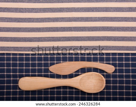 Wooden knife and spoon on off white and blue kitchen towels