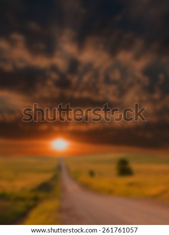 Blurred background of colorful sunset over a country road