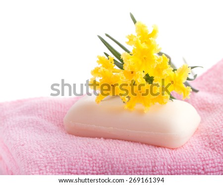 Soap on pink, soft wash cloth with a yellow wildflower on top, on white background