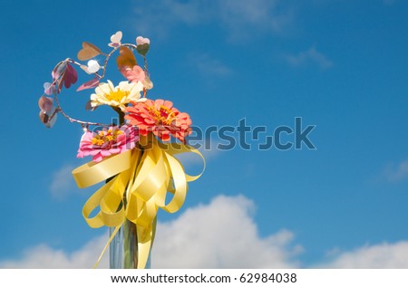 Brilliant flowers with a yellow ribbon and heart shaped decoration against blue skies with copy space