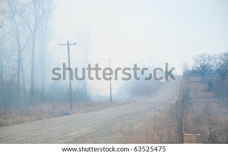 Heavy smoke and heat from a raging wildfire about to cross a country road