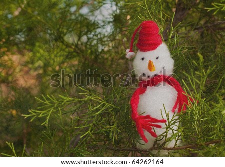 Happy Snowman ornament in a Christmas tree, antique textured image with copy space