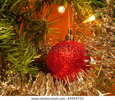 Red Christmas ball ornament in a tree lit by Christmas lights