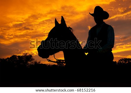 Silhouette of a horse and a rider against dramatic evening storm clouds