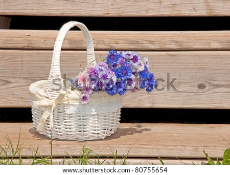 Wicker basket with flowers on rustic steps of a summer house