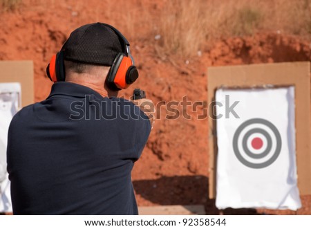 Man shooting at a target on an outdoor shooting range, focus on gun