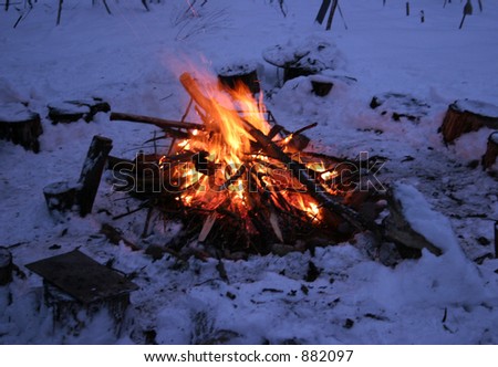 Camp fire in winter time, surrounded by snow.