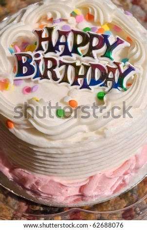 White iced Birthday Cake with colorful Happy Birthday sign.