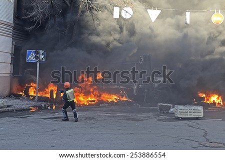 KIEV UKRAINE-FEBRUARY 18, 2014: Fire protecting by defend oneself protesters of armed special forces attack at first day of mass shooting at Euromaydan time. Protester in plastic helmet tosses a stone