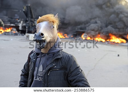 KIEV UKRAINE-FEBRUARY 18, 2014: Fire protecting by defend oneself protesters of  armed special forces attack at first day of mass shooting at Euromaydan time. Unknown protester in mask of horse head