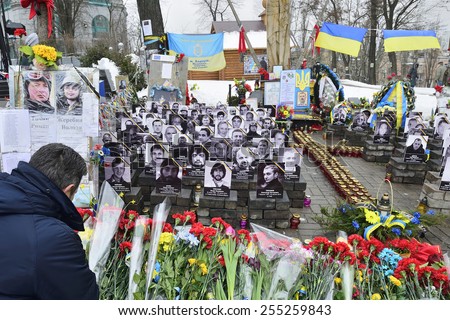 KIEV UKRAINE -FEBRUARY 20, 2015: Anniversary of mass shooting the armless Euromaidan demonstrators by armed special forces. Mourning men before the gallery of portraits of perished protesters