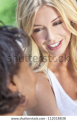 Two beautiful young women or girl friends chatting, one blonde, the other African American