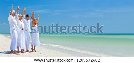 Panorama web banner photograph of two couples, generations of a family together holding hands and racing their arms in celebration on a deserted tropical beach