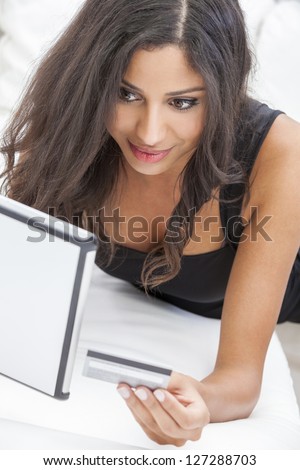 Beautiful mixed race Hispanic Latina woman using a credit card to shop on line using the internet and a tablet computer
