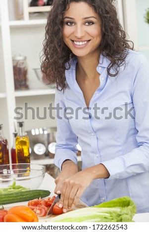 Beautiful young woman or girl preparing slicing healthy salad fresh food vegetables in kitchen at home
