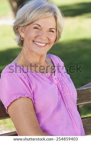 Portrait of an attractive elegant senior woman sitting outside with green grass behind her.