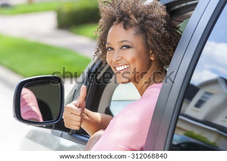 Beautiful young mixed race black African American woman giving thumbs up and driving a car
