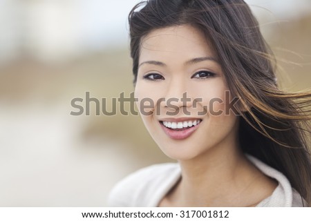 Outdoor portrait of a beautiful young Chinese Asian young woman or girl with perfect teeth