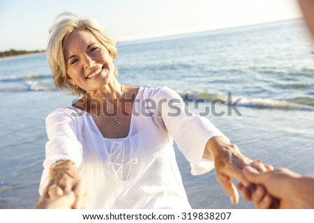 Happy senior man and woman couple walking or dancing and holding hands on a deserted tropical beach